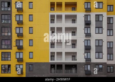Fragment of the wall of a multi-storey building in yellow, white and gray colors.