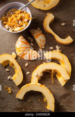 Sliced ??munchkin pumpkins and pumpkin seeds on a rustic wooden surface Stock Photo