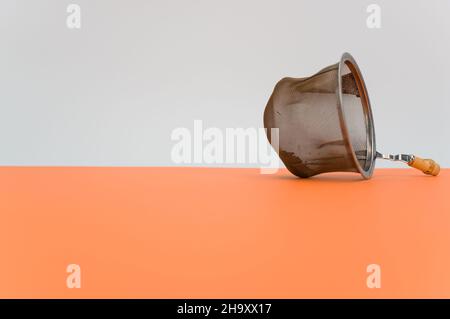 metal tea strainer on an orange paper background Stock Photo