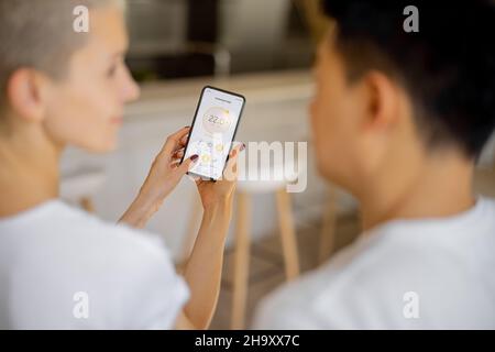 Couple using app of smart home on smartphone Stock Photo