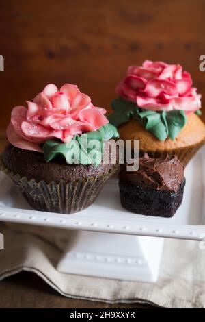 Cupcakes decorated with large sugar roses on a cake stand Stock Photo