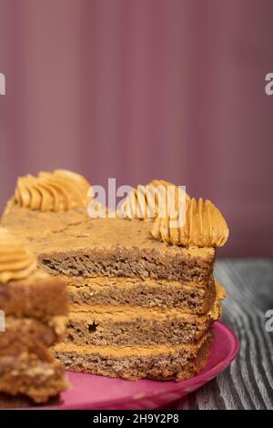Banana cake with butter cream. Lies on a plate, cut into pieces. On black pine boards. Close-up shot. Stock Photo