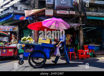 A male street vendor pushes  his food cart along the road in Bangkok Chinatown, Thailand. Stock Photo