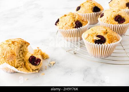 Closeup of homemade cherry muffins on cooling rack and white marble with copy space. Horizontal version. Low angle view. Stock Photo