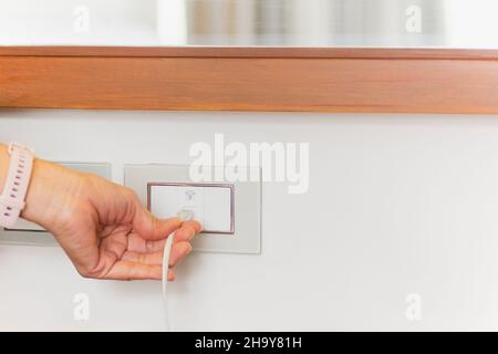 Female hand plug in internet cable wire into socket on the wall. Stock Photo
