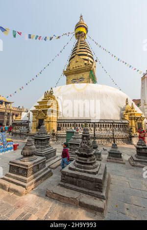 A little boy stands among the chaityas in the Swayambhunath temple complex in Kathmandu, Nepal.  The main stupa is behind. Stock Photo