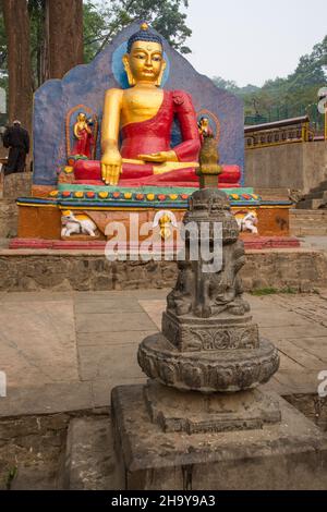 Very old stone-carved chaitya in front of a large painted Buddha statue, Swayambhunath temple complex, Kathmandu, Nepal. Stock Photo