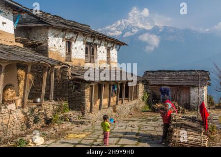 Children in front of a traditional farmhouse in the Himalayan foothill village of Dhampus, Nepal.  Behind is Machhapuchare. Stock Photo