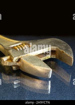 The Wrench rests upon glass table on black background. The Instrument for fastening the details. Stock Photo