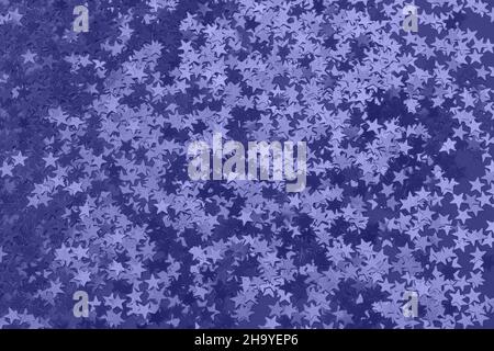 Metallic star shaped confetti on festive peri background. Stock Photo