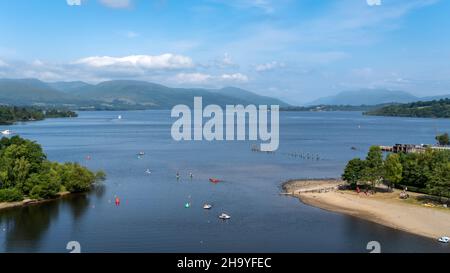 View over Loch Lomond from Lomond shores on a sunny summer day in Scotland, with people participating in water sports, Balloch, Scotland Stock Photo