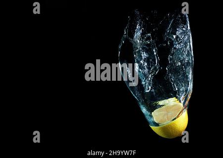 Halved citrus fruit in splash water against a black background Stock Photo