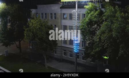 Old building illuminated by lanterns in modern night city. Stock footage. Top view of lighted old building in center of modern city at night. Beautifu Stock Photo
