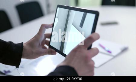 Virtual drawing of house on tablet. Stock. Businessman holding tablet with virtual reality project at home in boardroom. Digital 3D model of real esta Stock Photo