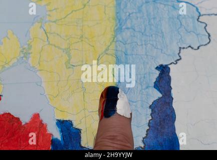 Tricolor painted forefinger on blurred background of Ukraine map Stock Photo