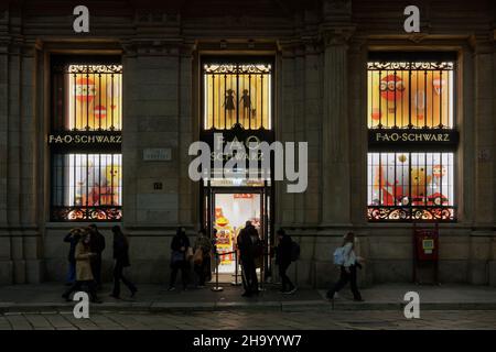 Milan, Italy FAO Schwarz toy store facade, with sign. Illuminated night view exterior of American brand shop selling toys at Via Orefici, with crowd outside. Stock Photo