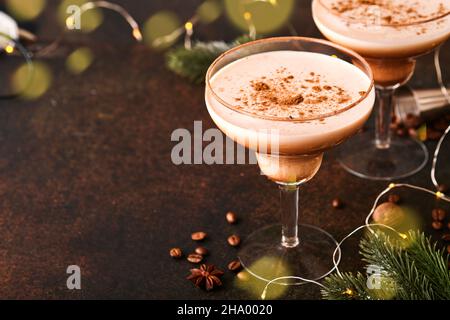 Alexander cocktail in cocktail glass on wooden table with shaker, nutmeg and small grater with Christmas decor on dark background. Beverage photograph Stock Photo