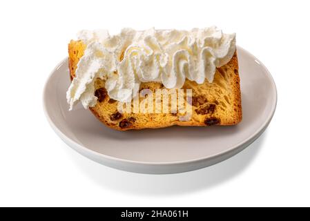 Slice of panettone cake with whipped cream in white plate isolated on white, typical Italian Christmas dessert Stock Photo