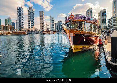 An traditional dhow transformed into a tourist tour boat, moored at the pier at the Dubai Marina, Dubai, UAE Stock Photo