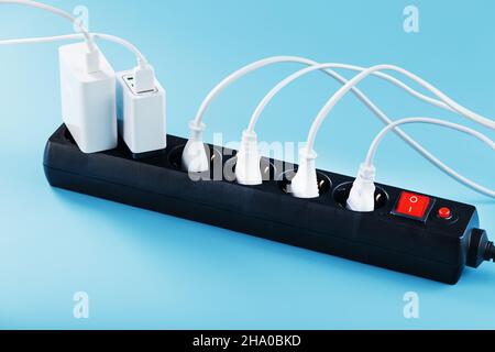 Surge protector with connected white wires of electrical appliances on a blue background. Free space Stock Photo