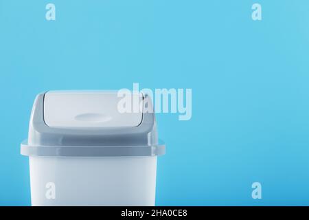 A white trash can with a lid on a blue background. Free space Stock Photo