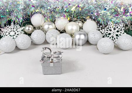 Silvery gift boxes on a blurred background with white and silver balls, garland and tinsel. Christmas card with white and silver balls, garland Stock Photo