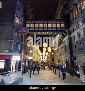 Illuminated raised walkway on Villiers Street near Charing Cross station on the right with an Underground Sign and festive lights. London. Stock Photo