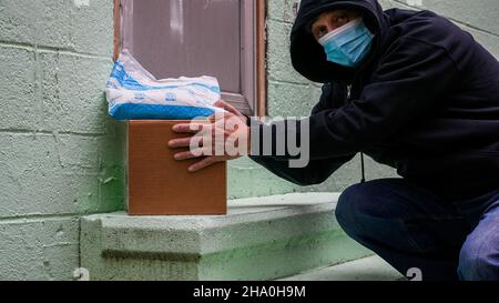 NORWALK,CT, USA - DECEMBER 8, 2021: Conceptual photo from man stealing  Amazon package with other box delivered to front door Stock Photo