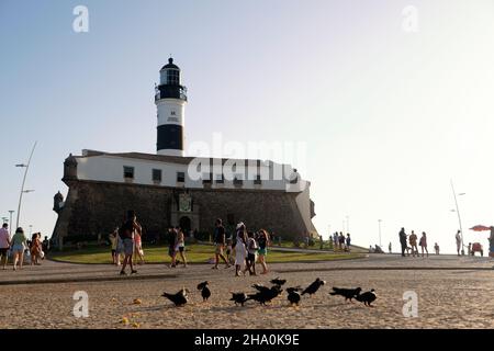 Salvador, Bahia, Brazil - July 29, 2021: View from below of Farol da Barra in Salvador, with pigeons eating corn on the ground and tourists strolling. Stock Photo