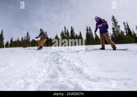 Snowboarders riding down a snowy mountain in Colorado Stock Photo