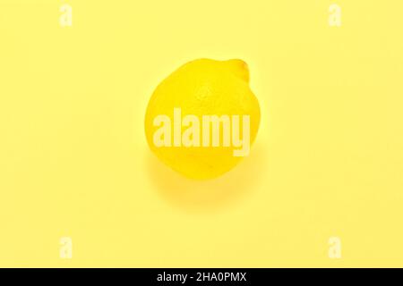 High angle view of a yellow lemon on a yellow background. Fresh lemon pattern on a vivid yellow background flat lay, top view Stock Photo