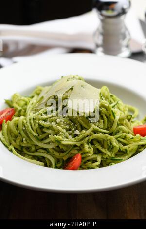 Spaghetti with pesto sauce and slices of parmesan cheese Stock Photo
