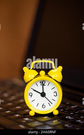 Yellow clock on a black computer laptop, business time management, success background Stock Photo