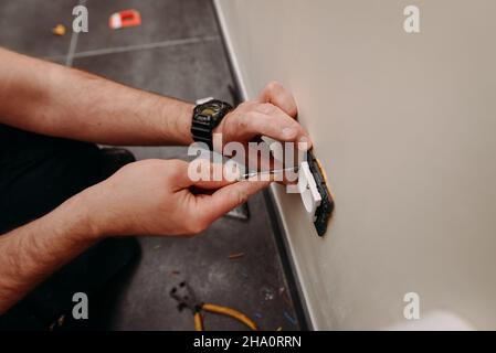 Electrician installs socket in wall of home Stock Photo