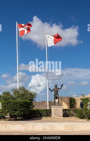 Statue of St John the Baptist & the flags of the Order of Knights of Malta & the Maltese flag. Fort St Angelo UNESCO World Heritage Site. Malta. Stock Photo