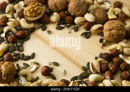Image with copy space surrounded by different nuts among which walnuts, cashews, pumpkin seeds, pistachios and sunflower seeds stand out Stock Photo