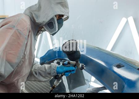 Professional car painter is painting in garage by airbrush. Stock Photo