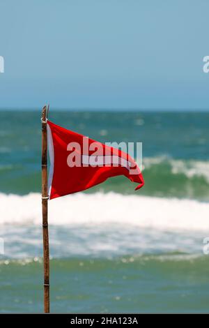 Red flag life guard danger warning sign on the beach. No swimming it's forbidden symbol, dangerous rip tide currents on water, enter at your on risk. Stock Photo