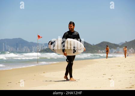 Surfer at beach. Surfing action water board sport. Men catching waves in ocean, isolated walking on sand. Young people lifestyle sports lessons Stock Photo