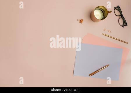 Still life in pastel pink tones with papers, red gold pens and pencils and reading glasses Stock Photo