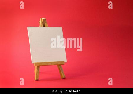 Easel for artists miniature on bright red background. Art minimal concept close up Stock Photo