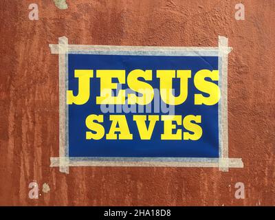 Stockholm, Sweden - September 4, 2020: A small poster taped on a wall with the christian message "jesus saves" with blue background and yellow text sa Stock Photo
