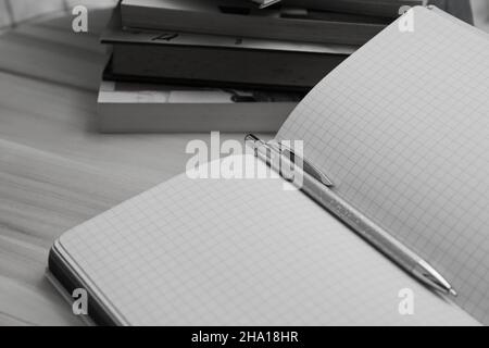 Close-up of a notebook or diary for notes with the blank sheets with a pen and some books in the background Stock Photo