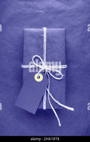 Wrapped gift box with tag over lilac very peri color background. Color of the year 2022 very peri toned. Copy space Stock Photo