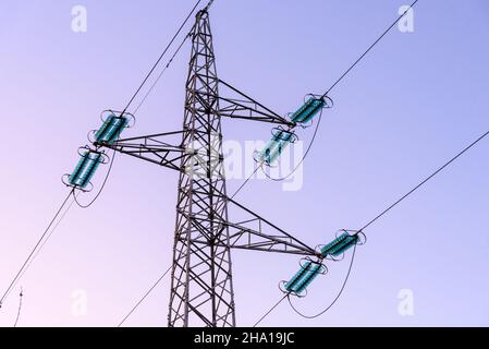 Electricity pylon supporting high voltage cables against clear sky at dusk Stock Photo
