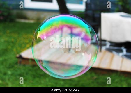 Closeup of a large bubble outside, garden in background and reflected in bubble. Stock Photo