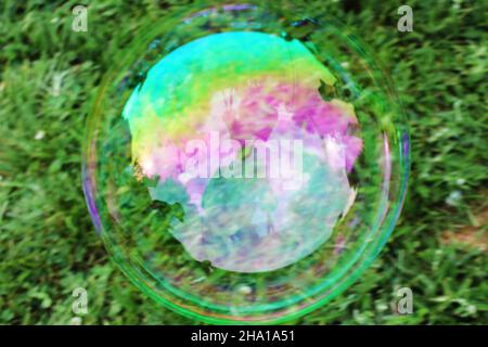 Closeup of a large bubble outside, garden in background and reflected in bubble. Stock Photo