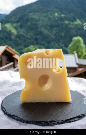 Cheese collection, French cow cheese emmental and french mountains village in Haute-Savoie in summer on background Stock Photo