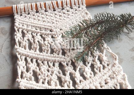 Weaving from cotton thread decorative work from 100% cotton in macrame style, hand made on a concrete wall. Women's hobby. Stock Photo