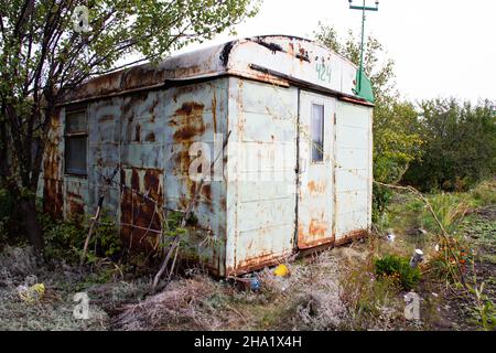 Apocalypse concept photo. Doomsday Post-Apocalyptic Abandoned House. Old metal wagon of apocalyptic appearance. View of the land after the Apocalypse. Stock Photo